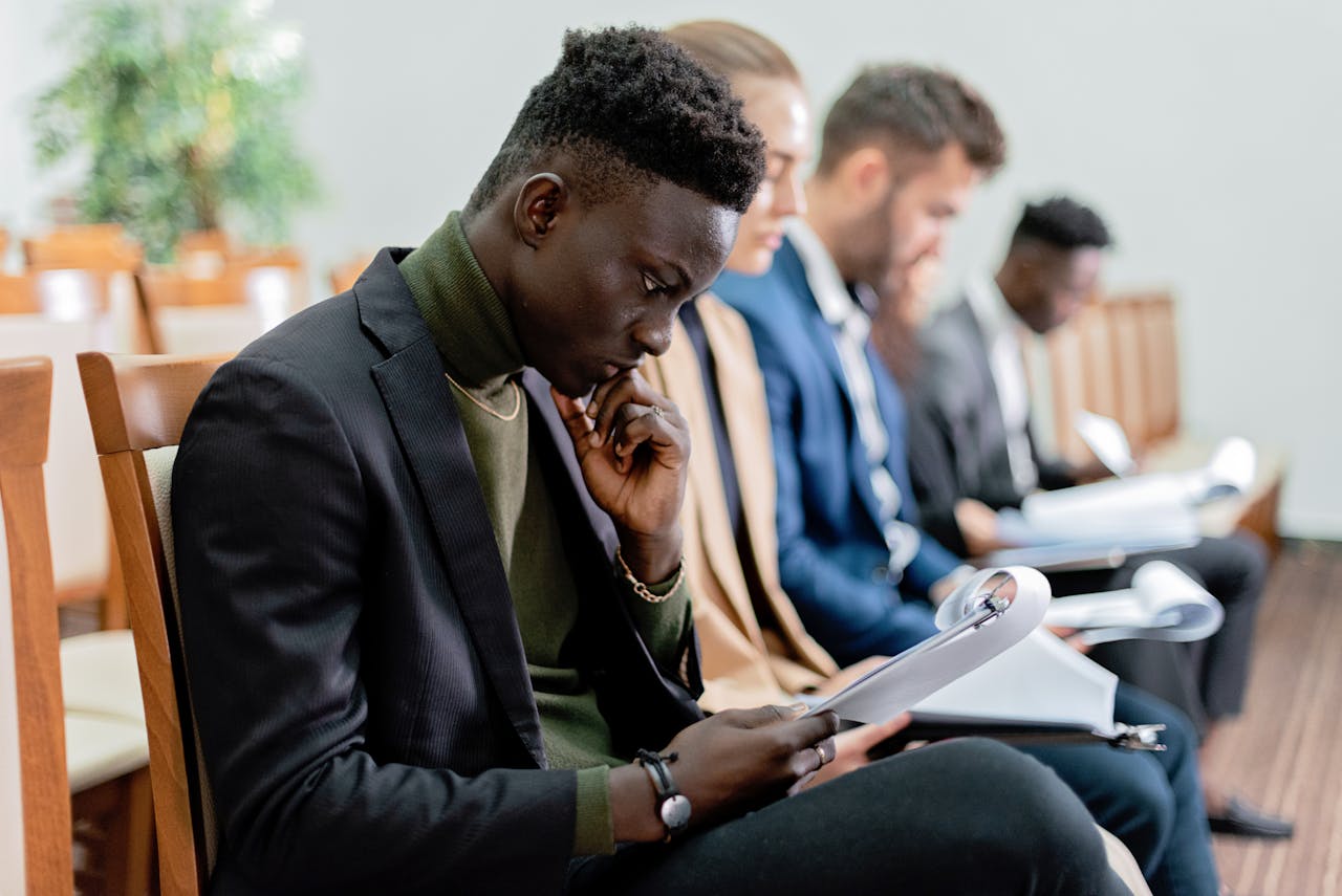 Four diverse professionals in a focused business meeting, reviewing documents in an office setting.